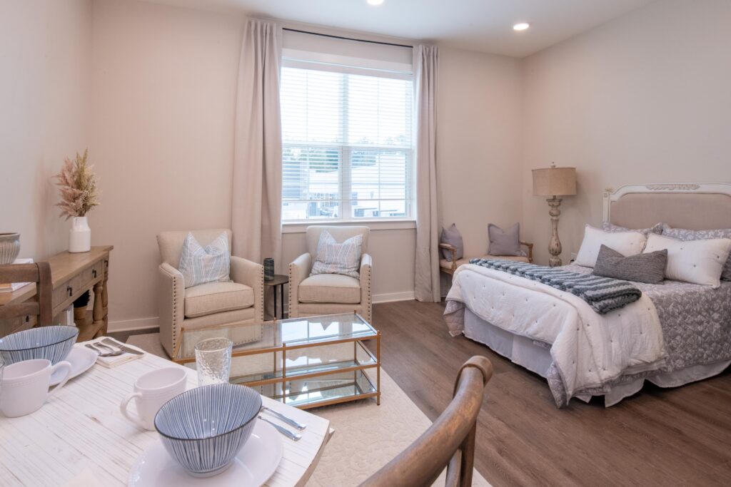 Interior image of a resident's studio apartment with bed, chairs, and small kitchen table.