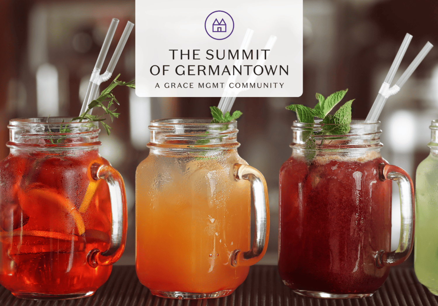 Three colorful iced drinks in mason jars with mint garnish and straws on a bar, overlaid with a white banner that reads 'THE SUMMIT OF GERMANTOWN – A GRACE MGMT COMMUNITY'