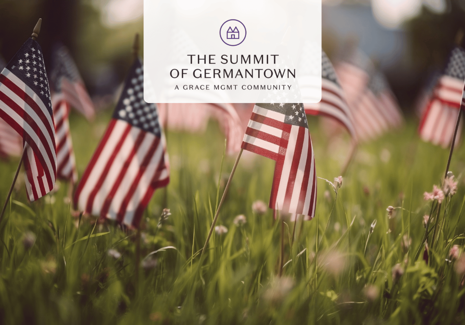 Small American flags planted in a grassy field with a translucent logo reading 'The Summit of Germantown – A Grace Mgmt Community' overlayed